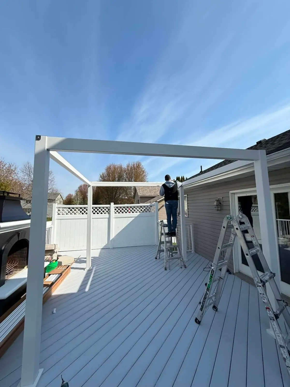 White pergola frame being installed over a newly finished composite deck